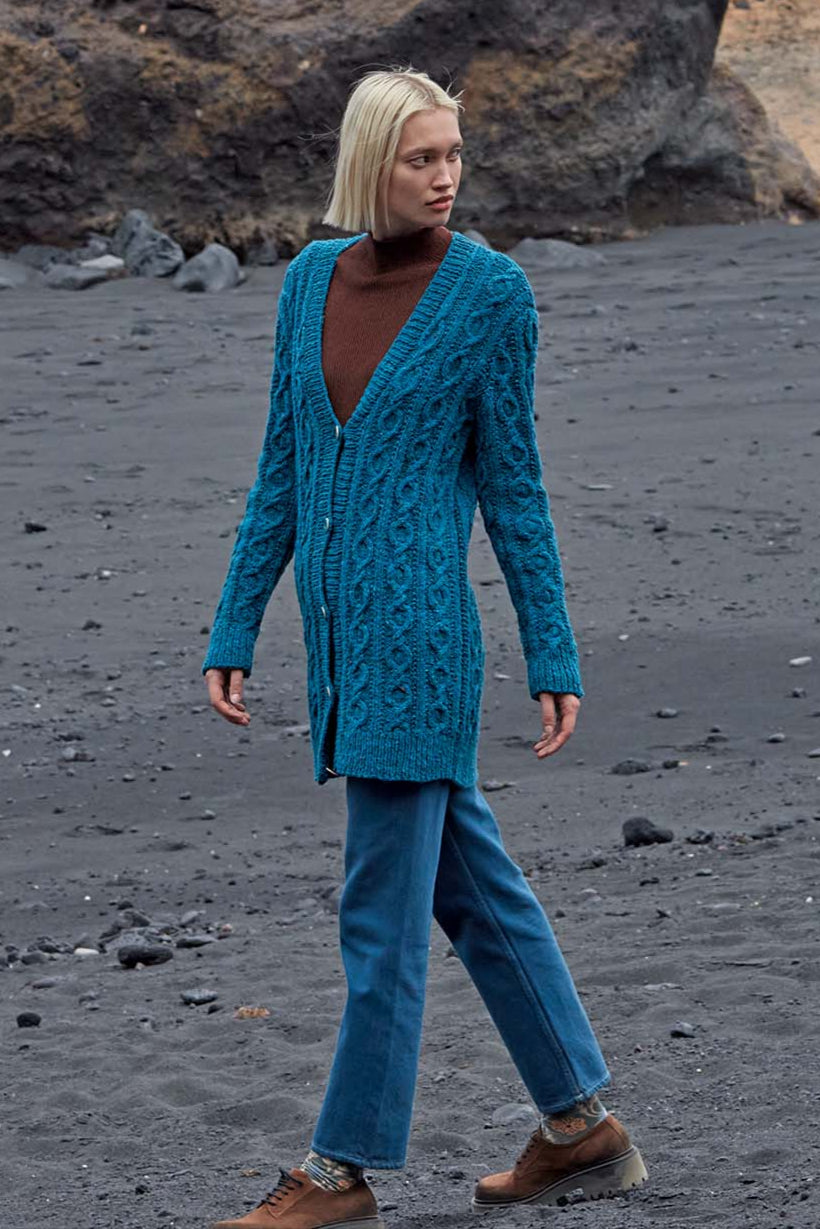 Model draagt blauw gebreid kabelvest Jemima, gemaakt met Lang Yarns Donegal Tweed+ wol