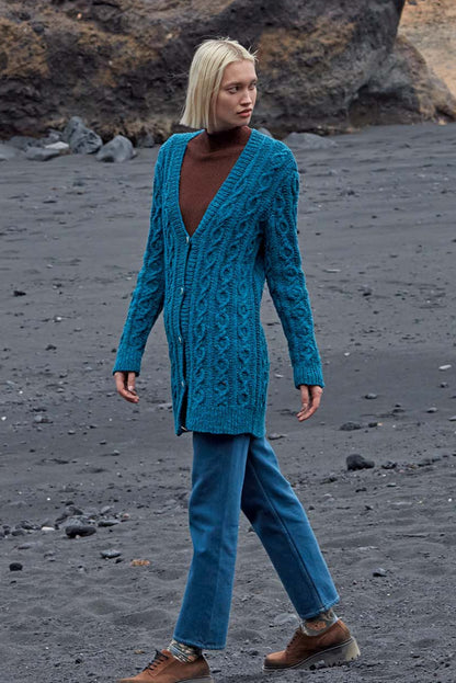 Model draagt blauw gebreid kabelvest Jemima, gemaakt met Lang Yarns Donegal Tweed+ wol