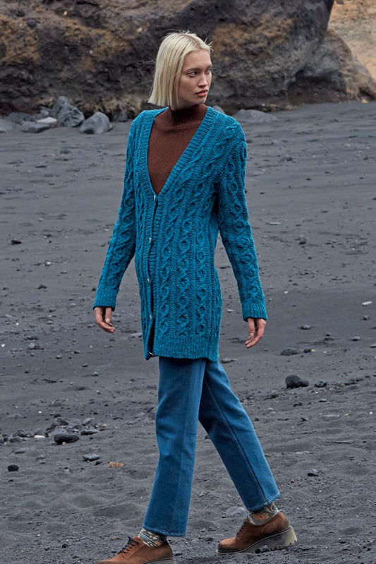 Model draagt blauw gebreid kabelvest Jemima, gemaakt met Lang Yarns Donegal Tweed+ wol