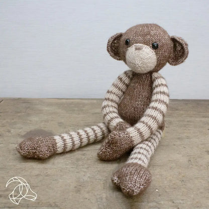 Gebreide Malinda Monkey uit het Hardicraft breipakket, zittend met lange gestreepte armen en benen.